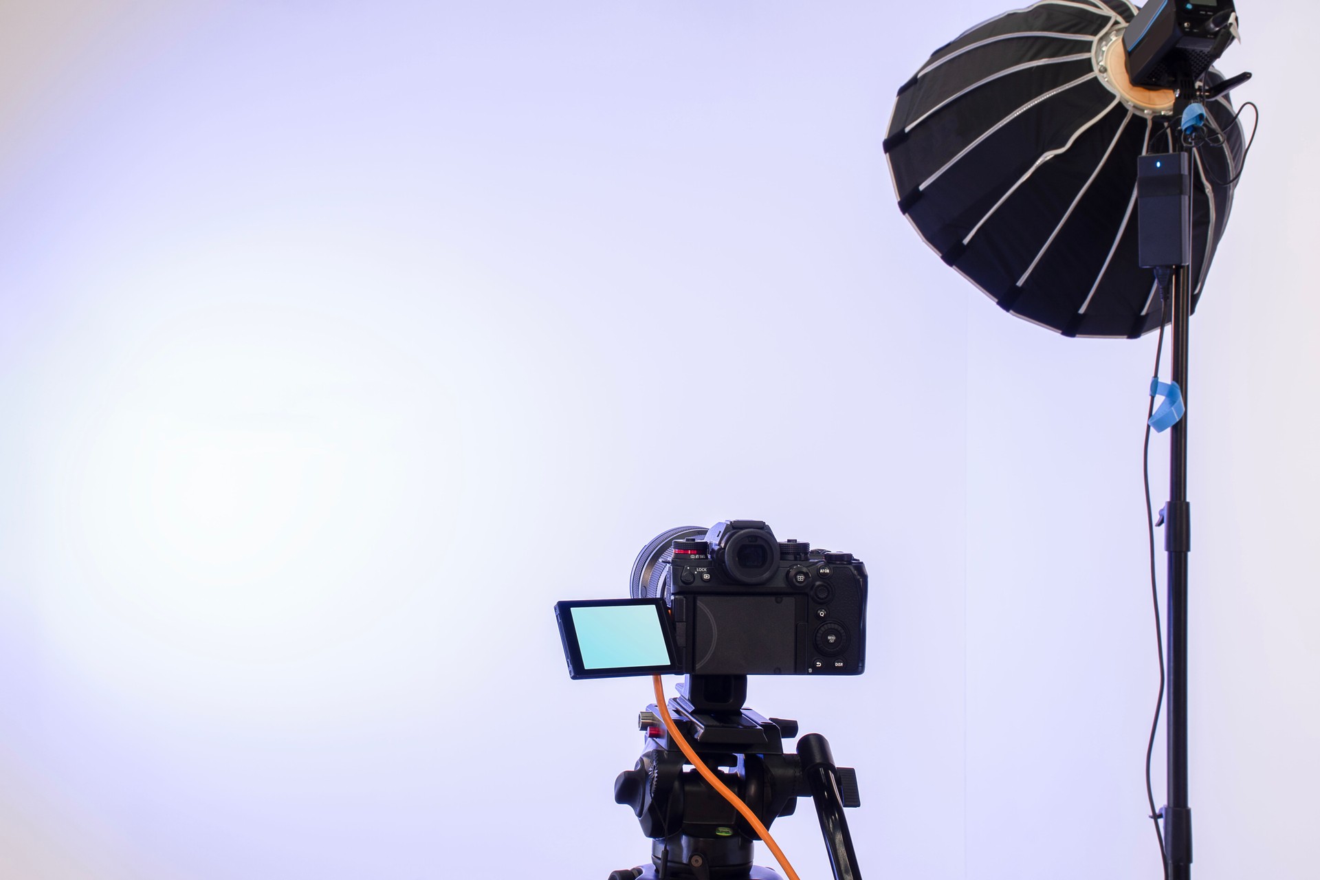 Back view camera on tripod and studio lights with blank screen backdrop