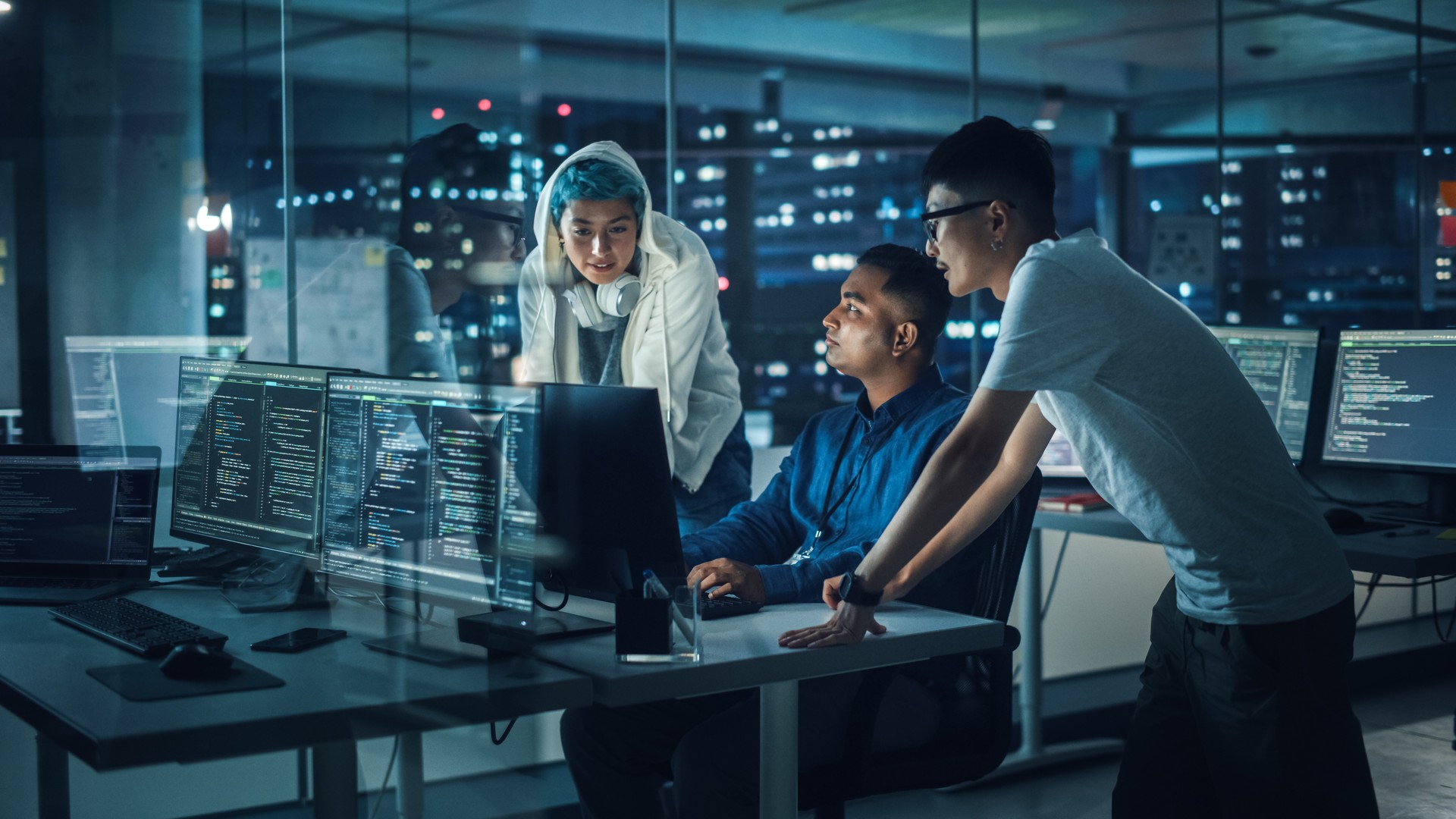 Diverse Team of Professionals Meeting in Office at Night: Brainstorming IT Programmers Use Computer Together, Talk Strategy, Discuss Planning. Software Engineers Develop Inspirational App Program